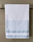 White towel with light blue stripes hanging on a chrome towel bar in a modern bathroom