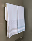White striped towels hanging on a modern chrome towel bar in a tiled bathroom