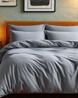 Gray bedding set on a bed with wooden headboard and nightstand in a bedroom setting.