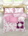 Floral bedding set with pink and purple accents on a bed in a bright room.