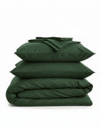 Stack of green cotton sateen bedding bundle including a duvet cover, two pillowcases, and a flat sheet on a white background