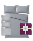 Grey bedding set with patterned pillows and a purple throw blanket on a white background