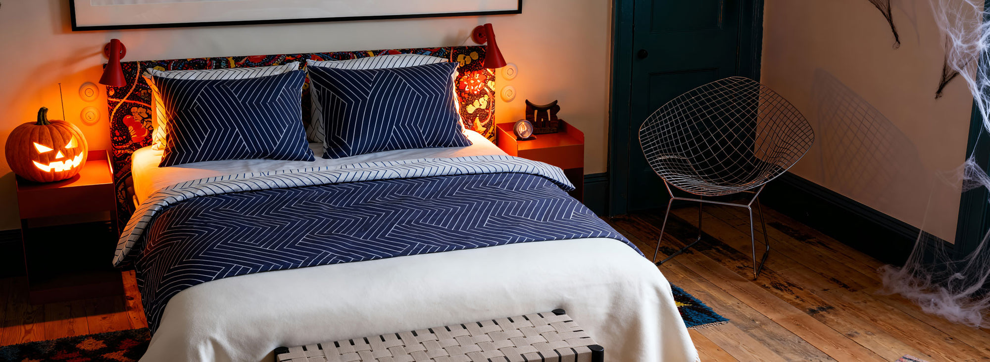 Bedroom with blue and white bedding, Halloween decorations, and a small table with a cat.