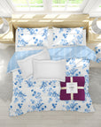 Floral bedding set with blue and white patterns on a bed in a bright room.