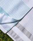 White and teal striped peshtemal towel on grass, hotel spa beach cotton textile