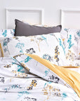 Floral duvet cover set with yellow, teal, and gray botanical print on a white bed
