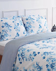 Blue floral duvet cover set on bed with white background and decorative vase