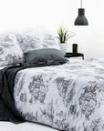 Grey toile de Jouy duvet cover set on bed with black lamp and plant