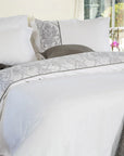 White bedding set with gray floral damask accents on a neatly made bed