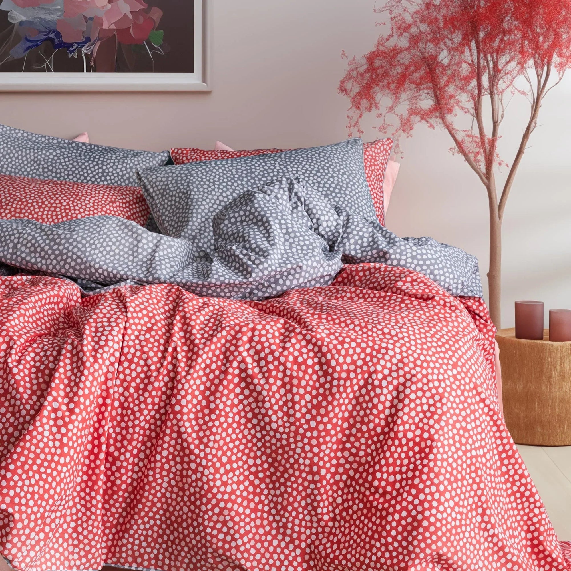 Polka dot red and gray bedding set in a modern bedroom with pink decor and framed art
