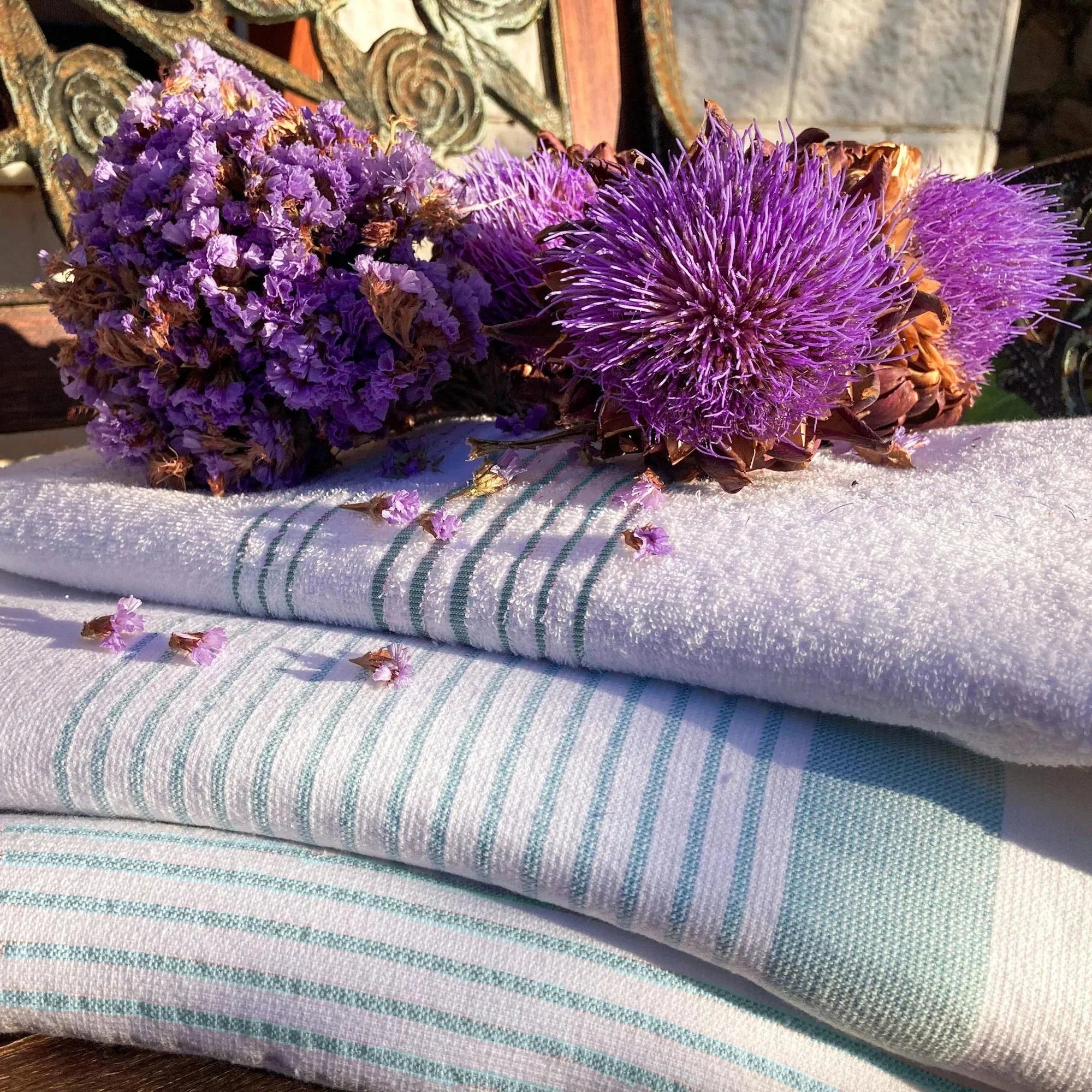 White stone striped peshtemal towels with purple flowers on top, outdoor setting