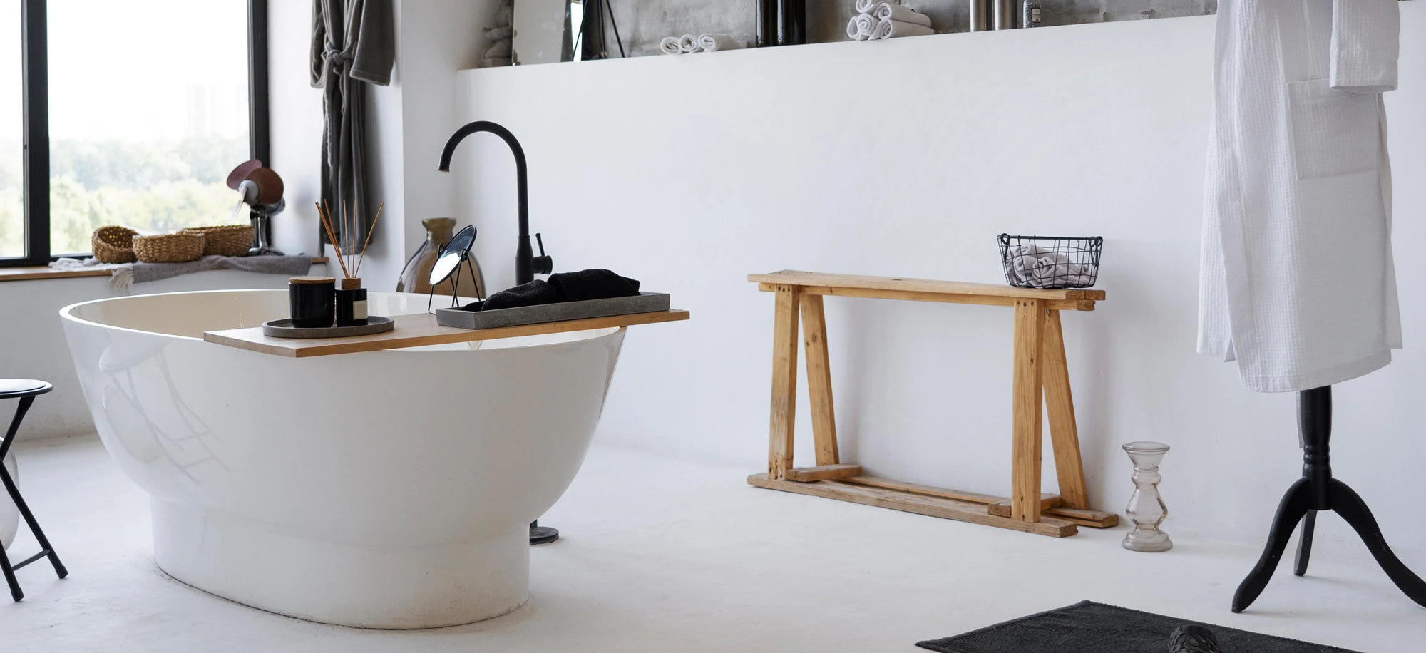 Modern bathroom with white freestanding tub, wooden bench, bathrobe, spa decor, large window