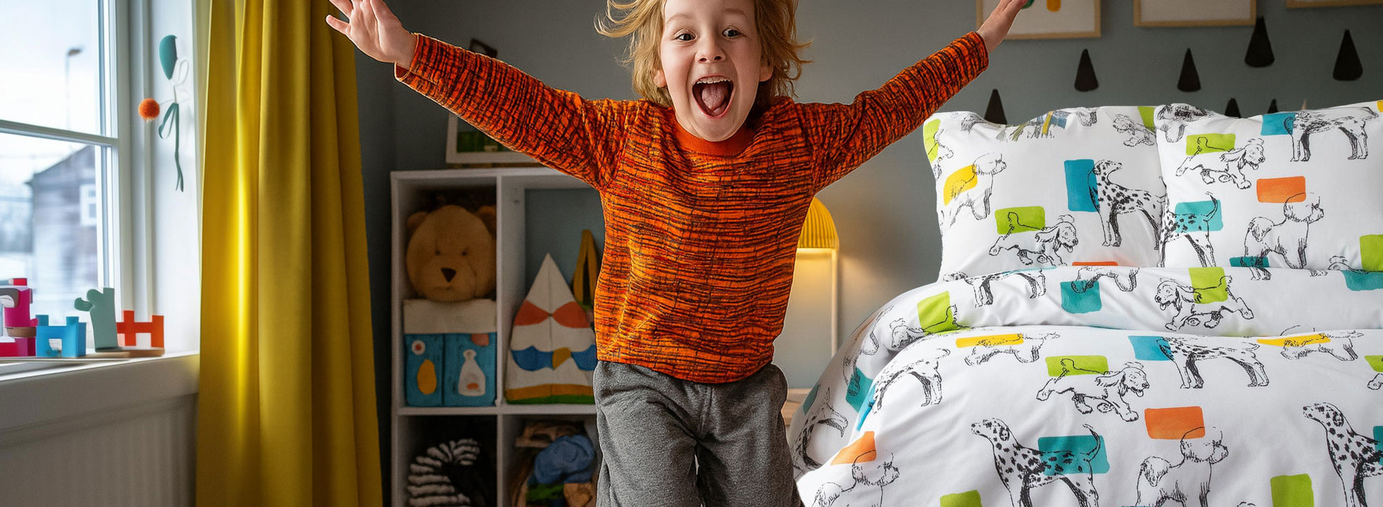 back to school student boy in an orange sweater jumping in a bedroom with colorful bedding and shelves.