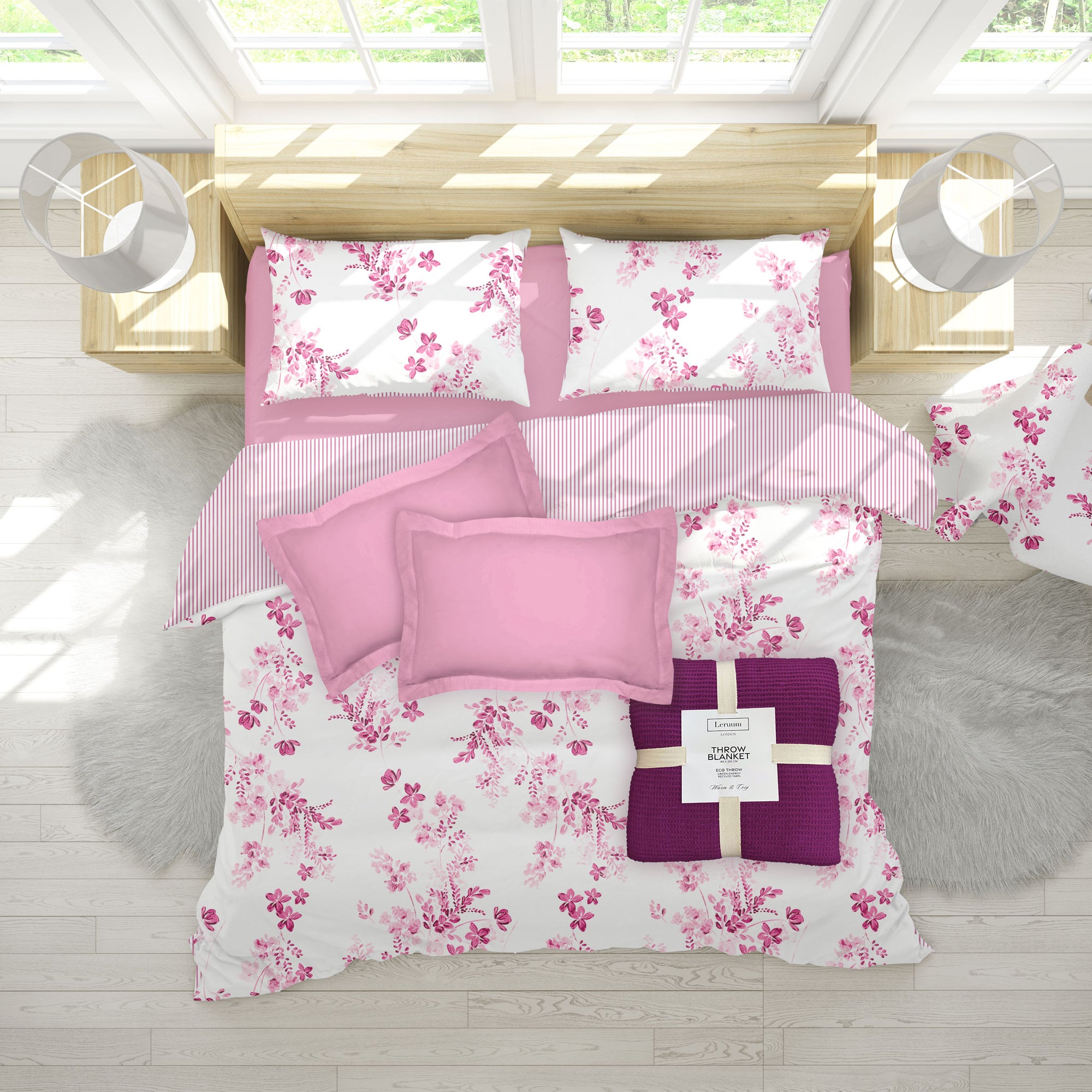 Floral bedding set with pink and purple accents on a bed in a bright room.
