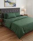 Bedroom with green bedding and a gray upholstered headboard.