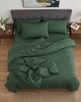 Green cotton sateen bedding set on a bed in a bedroom with wooden floors and side tables.