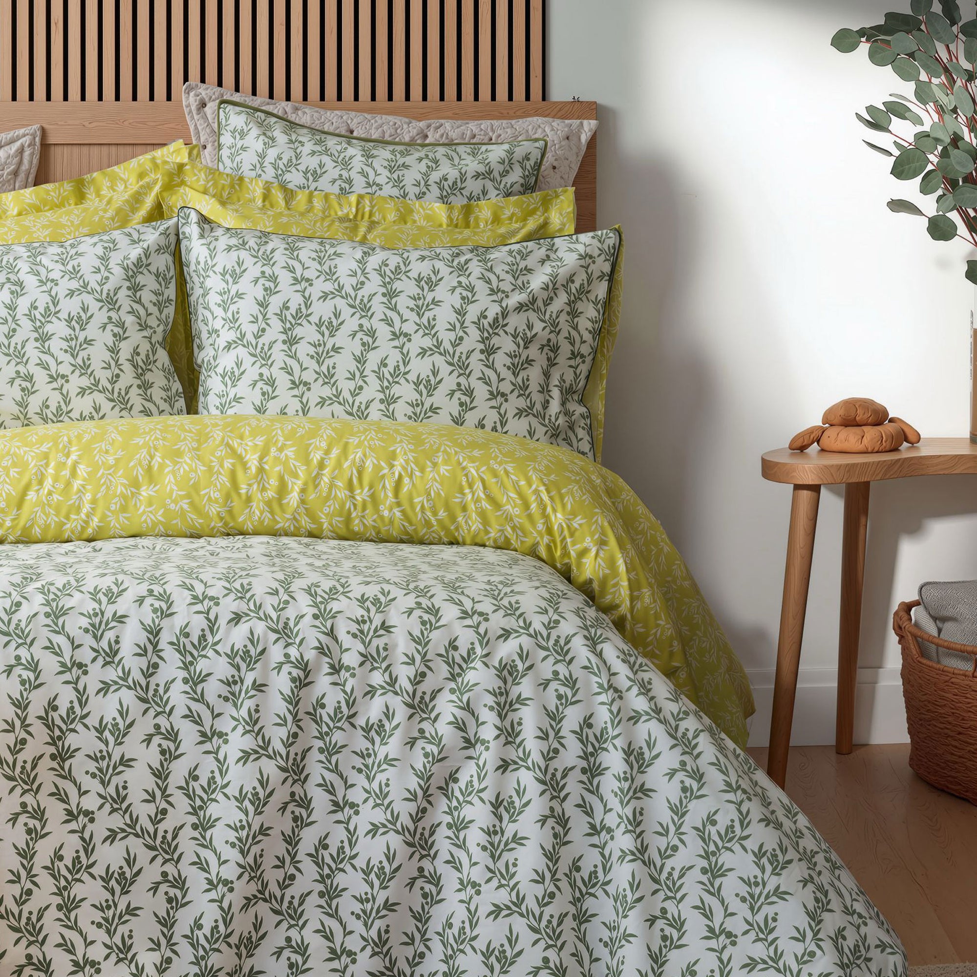 Bedding set with green and white floral pattern in a bedroom setting.
