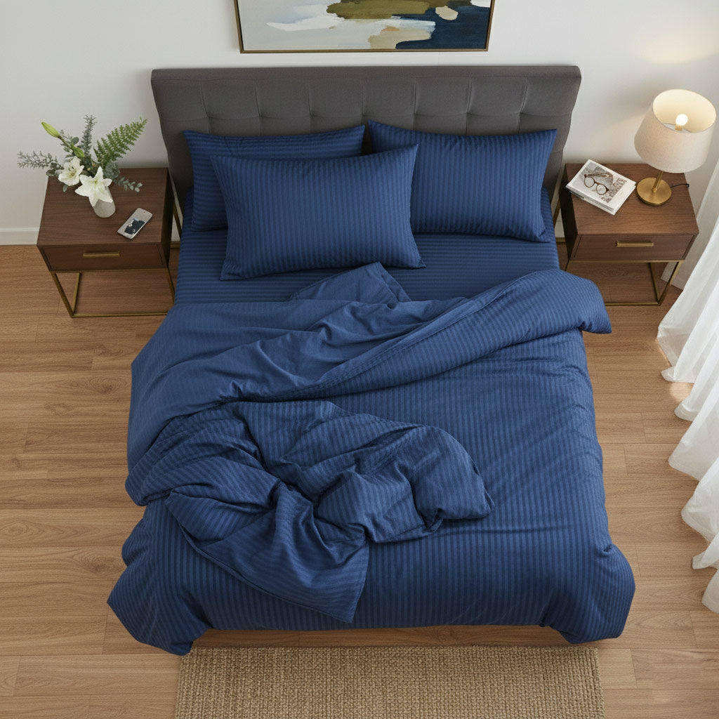 Blue cotton sateen bedding set on a bed in a bedroom with wooden floors and side tables.
