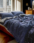 Bed with blue and white striped bedding in a bedroom setting.