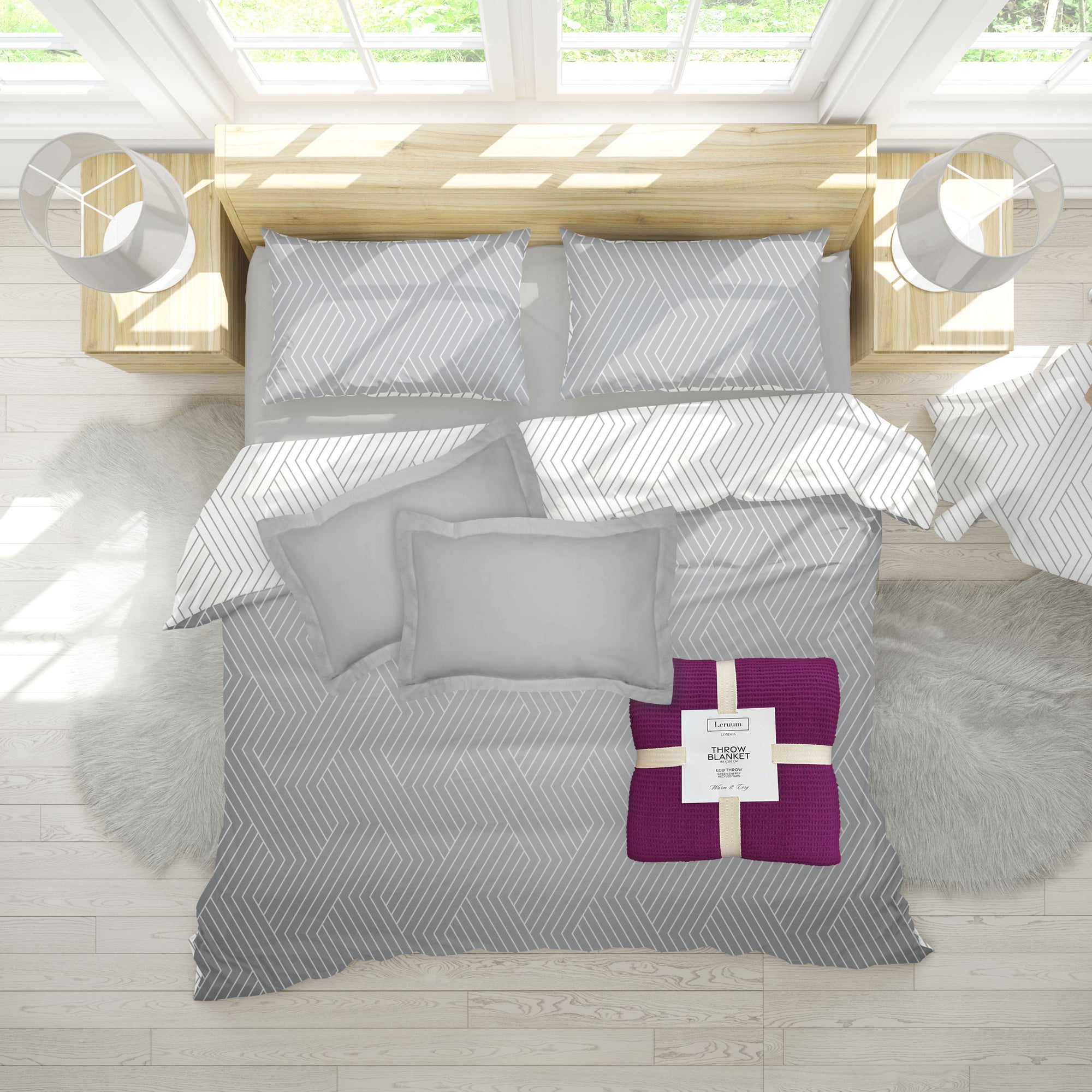 Gray bedding set with a purple throw on a bed in a bright room.
