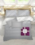 Gray bedding set with a purple throw on a bed in a bright room.
